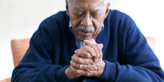 En äldre man ber.