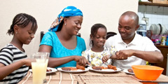 Un mari et sa femme mangent avec leurs deux filles dans une ambiance joyeuse