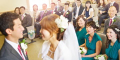 El novio y la novia intercambian votos matrimoniales en el Salón del Reino mientras los invitados los observan