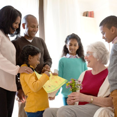Uma família dando atenção a uma mulher idosa de outra etnia