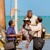 Két Jehova Tanúja a tengerparton megmutat egy bibliaverset egy férfinak