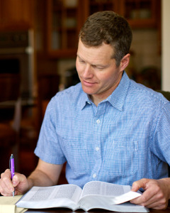 Mężczyzna robi notatki, studiując Biblię