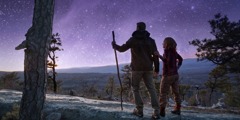 Семейна двойка се разхожда в планината под звездното небе