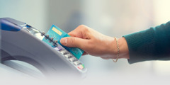 A woman inserts a bank card into an electronic card reader