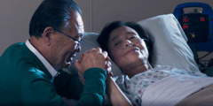 一位姊妹躺在医院的病床上，她先生握着她的手，和她一起祷告