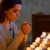女子在燃着的蜡烛前祷告，手里拿着念珠