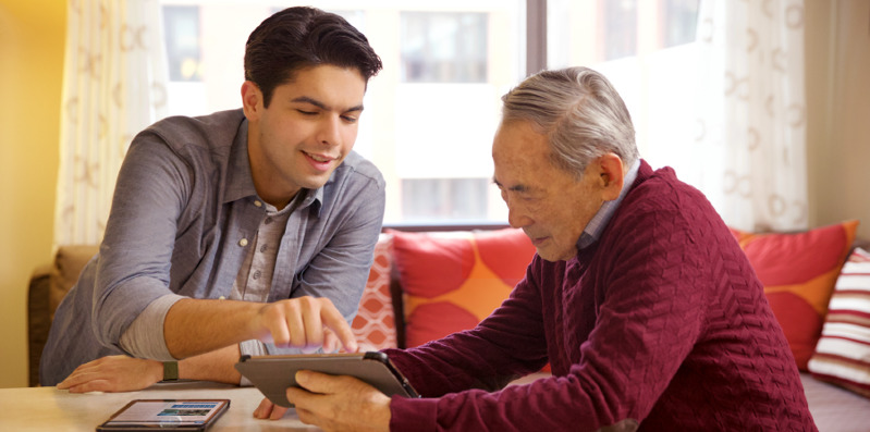 Ένας νεαρός αδελφός βοηθάει έναν ηλικιωμένο να εξοικειωθεί με την ηλεκτρονική συσκευή του