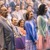 Una ragazza sta in piedi insieme ad altri candidati al battesimo, mentre i genitori la guardano con orgoglio