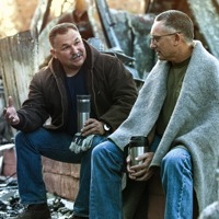 Two men sit among the rubble of a devastated building