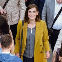 A young woman smiles and confidently walks along a crowded sidewalk