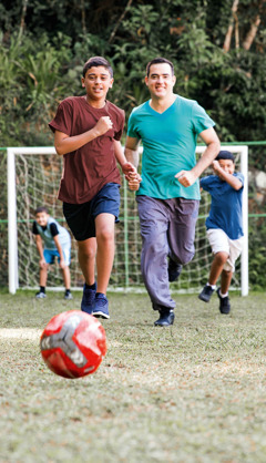 A brother plays soccer with young brothers