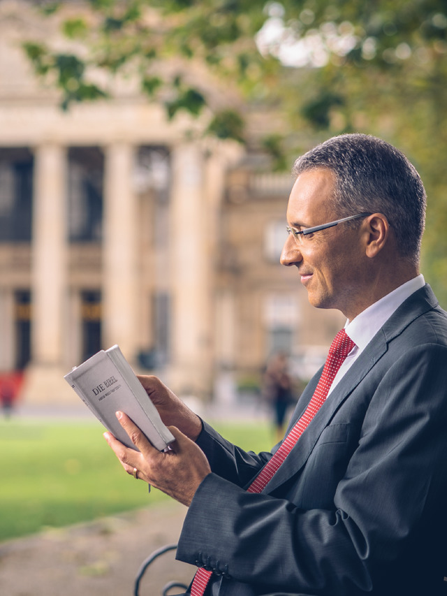 Un uomo legge la Bibbia su una panchina di fronte a un edificio del governo.