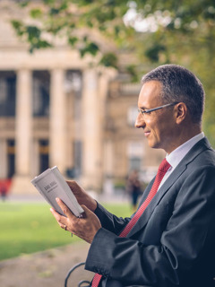 En mand læser i Bibelen mens han sidder på en bænk foran en regeringsbygning.