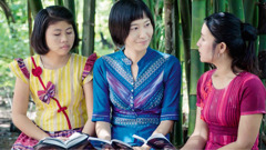 A scene from the video ‘Field Missionaries​—Workers in the Harvest.’ A field missionary and another sister studying the Bible with a woman.
