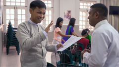 A scene from the video ‘Field Missionaries​—Workers in the Harvest.’ A field missionary brother in a sign-language field discusses with another brother an application for special service.