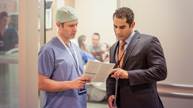 A Hospital Liaison Committee member giving a public information kit to a doctor.
