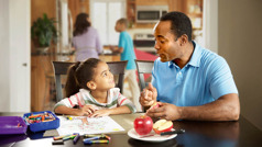 El mismo papá habla con su hija mientras ella pinta un manzano. Él le señala unas manzanas que hay en un plato sobre la mesa.