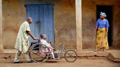 Dos hermanos que van predicando se acercan a una mujer. Uno de ellos está en una silla de ruedas y el otro lo va empujando.