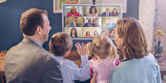 Γονείς με τα δύο μικρά παιδιά τους κάνουν συναναστροφή με τους αδελφούς της εκκλησίας τους μέσω βιντεοδιάσκεψης.