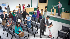 Brothers and sisters before a congregation meeting. 1. They greet and talk with one another. 2. A brother shows a sister something posted on the information board. 3. A sister places a donation in the contribution box. 4. A brother behind the counter hands literature to a sister. 5. A brother adjusts a microphone on the platform. 6. A brother and his young son clean.