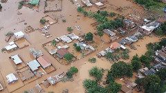 Кадър от клипа „Големи наводнения в Бразилия“. Поглед отвисоко на частично потопени къщи и дървета в наводнен квартал.