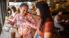 En una cafetería, una hermana joven escucha con atención a una hermana de mayor edad.