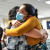 Two sisters wearing face masks happily embracing each other at a Kingdom Hall.