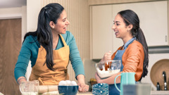 A mother and daughter talking happily as they prepare a meal together.