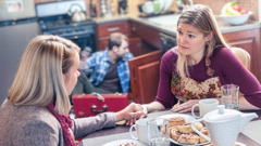 Un matrimonio ayuda a una hermana. La esposa la escucha con empatía mientras su esposo repara algo en la cocina.