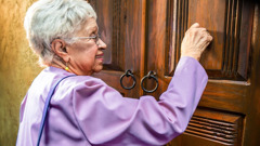 An elderly sister knocking on a door while in the ministry.