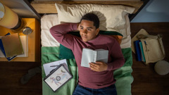 A teenage boy meditating on a scripture he just read. Next to him is a tablet showing a scene from the video “My Teen Life​—How Can I Fight the Pressure to Have Premarital Sex?” The scene depicts Joseph running away from Potiphar’s wife.