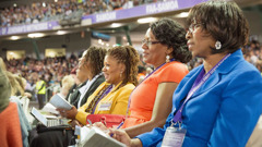 Sisters listening attentively and taking notes at a convention.