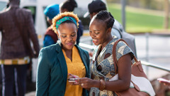 A sister witnessing to a woman at a taxi stand.