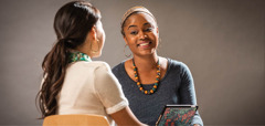 Une sœur enseigne la Bible à son étudiante, qui a un grand sourire.