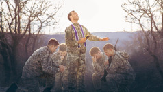 Ksiądz w mundurze modli się za grupę żołnierzy.