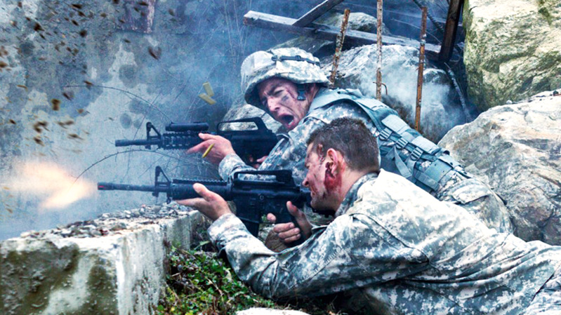 Soldați în timpul unui război trag cu pușca din spatele unei baricade