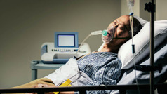 Άρρωστος άντρας σε κρεβάτι νοσοκομείου.