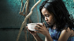 Una bambina che soffre la fame tiene tra le mani una ciotola.