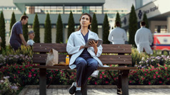 Sykepleieren sitter på en benk utendørs i lunsjpausen og ser opp mot himmelen etter at hun har lest i Bibelen.