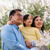 Doi părinți împreună cu fiica lor admiră un cireș înflorit