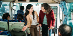 Egy nő átadja a helyét a buszon egy idős asszonynak.