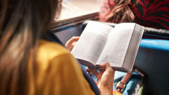A sister reading the Bible while riding on a bus.