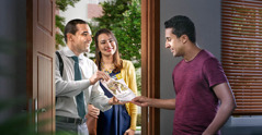 A couple offering the brochure “Enjoy Life Forever!” to a man at his home.