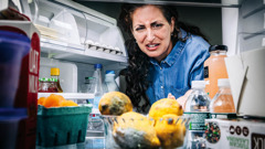 Une femme regarde avec dégoût des aliments pourris dans un réfrigérateur.