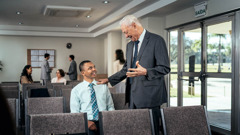 Un anziano incoraggia un giovane fratello che è seduto per conto suo nella Sala del Regno.