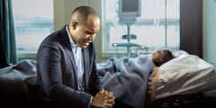 En bror beder for sin syge hustru der ligger i en hospitalsseng.