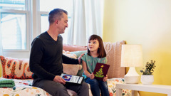 A father discussing an article from jw.org with his young daughter. The daughter is holding a Christmas card.