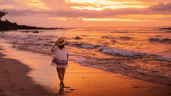 Au coucher du soleil, une sœur marche le long d’une plage et regarde les vagues rouler vers le rivage les unes après les autres.