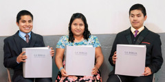 Marcelo, Yomara, and Hiver each holding a volume of the Spanish “New World Translation” in braille.