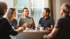 Un grupito de hermanos comiendo juntos. Uno de ellos está hablando y los demás lo escuchan con atención.